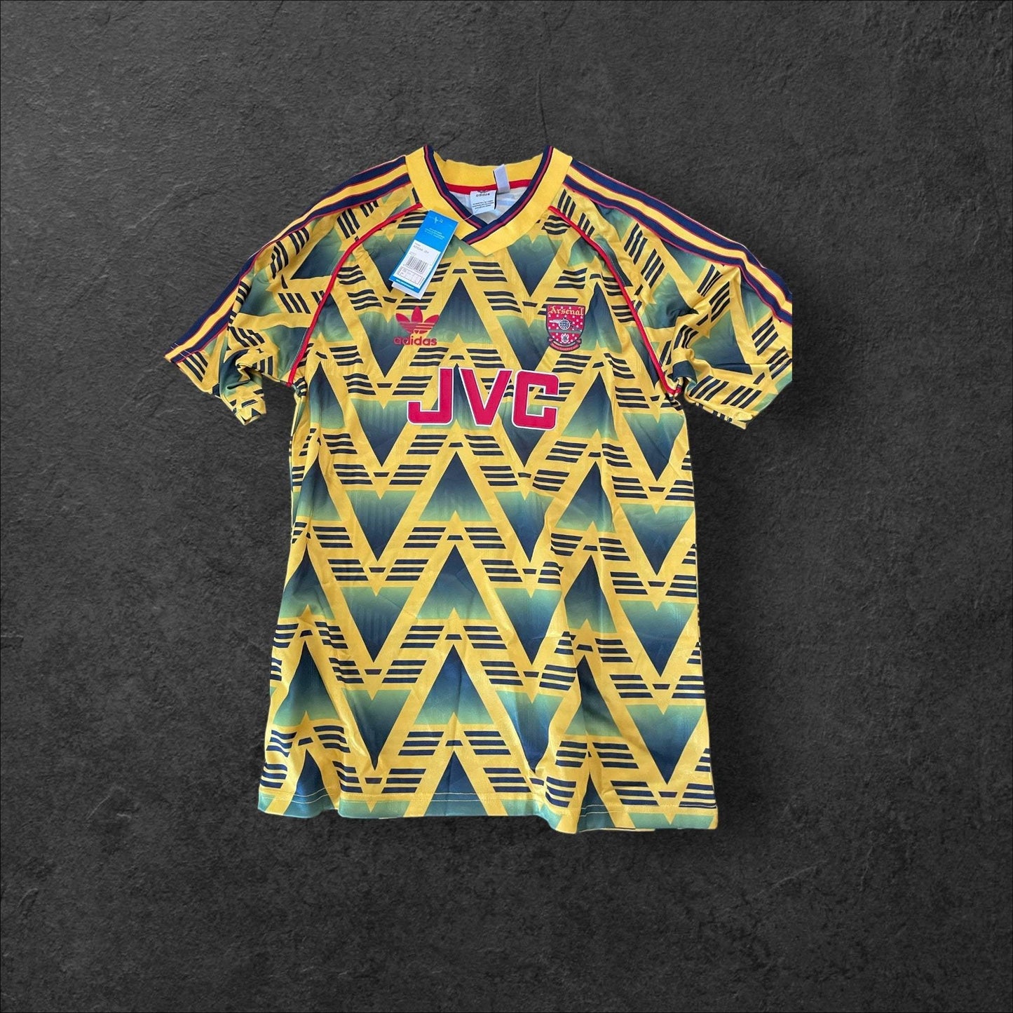 Arsenal Away 1991-93 jersey with "bruised banana" zigzag pattern in yellow and navy, featuring classic crest and sponsor logo.